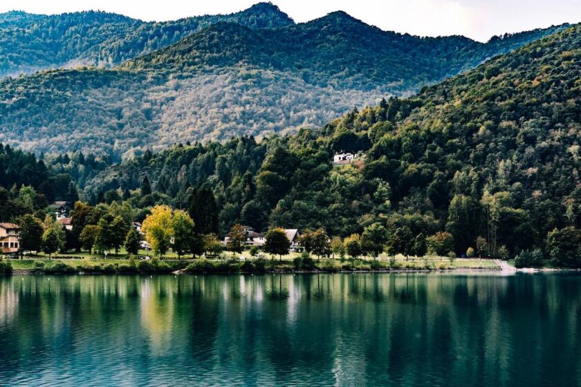 Specchio d’acqua limpido in Trentino, immerso tra boschi e montagne al tramonto