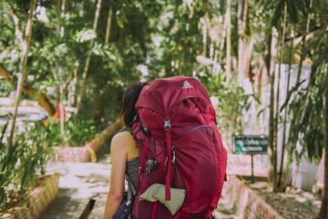 Viaggiatrice con zaino guarda una città al tramonto – viaggio economico in solitaria