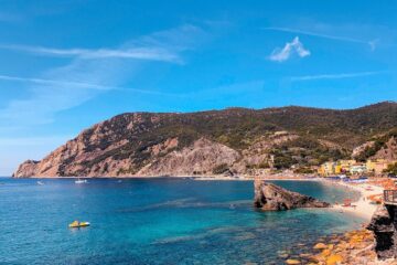 Spiaggia ligure con mare turchese e borghi colorati