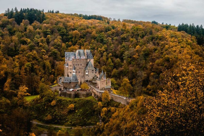 Burg Eltz immerso nella foresta, avvolto dalla nebbia mattutina.