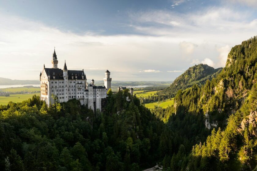 Castello di Neuschwanstein al tramonto, tra boschi e montagne bavaresi.