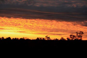 Il monolite di Uluru al tramonto con cielo rosso e atmosfera sacra