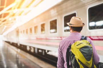 Viaggiatore con zaino in spalla in una stazione ferroviaria in India, viaggio zaino in spalla