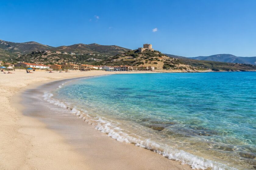 Spiaggia di Bosa Marina in Sardegna con mare azzurro e torre aragonese sullo sfondo